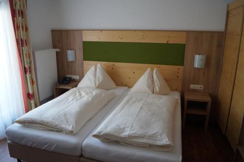 a bed with white sheets and pillows on it at Hotel Wechselberger by Alpeffect Hotels in Saalbach Hinterglemm