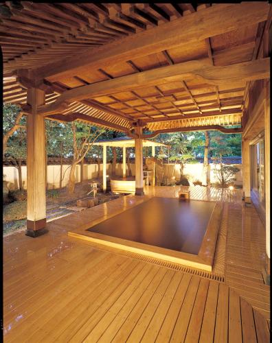 a large swimming pool under a pavilion on a wooden deck at Hotel Saginoyu in Suwa