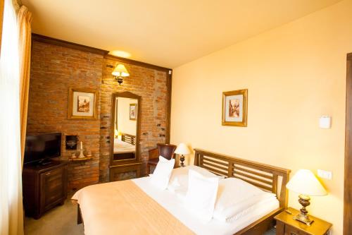 a bedroom with a white bed and a brick wall at Hotel Bella Muzica in Braşov