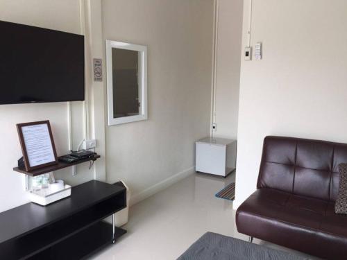 a living room with a brown leather couch and a television at Baan Chan Suan in Nong Nam Daeng