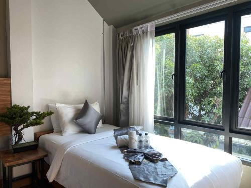 a white bed in a room with a large window at Lanna Tree Boutique Hotel in Chiang Mai