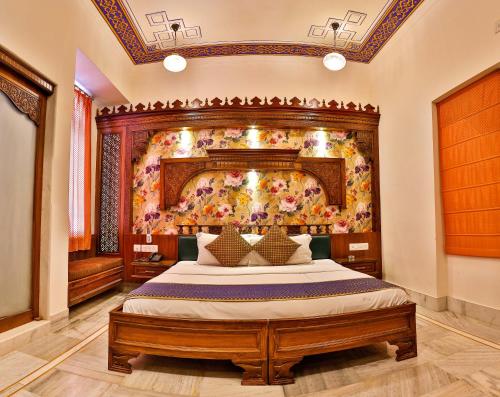 a bedroom with a large bed with a painting on the wall at Hotel Pearl Palace in Jaipur