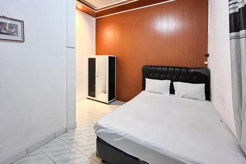 a bedroom with a bed with a wooden headboard at Kostel 99 Pangkal Pinang RedPartner in Pangkal Pinang