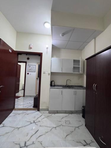 a kitchen with white cabinets and a tile floor at Cozy Studio Apartment near union Metro in Dubai