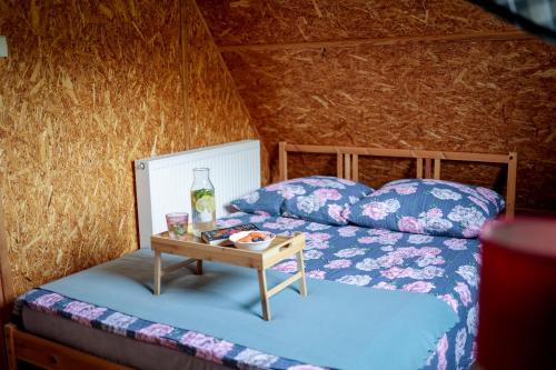 a bed with a table with a bottle on it at Chatki Szymonówko in Liksajny