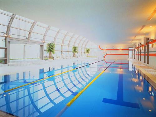 a large swimming pool with blue water in a building at Rembrandt Hotel Oita in Oita