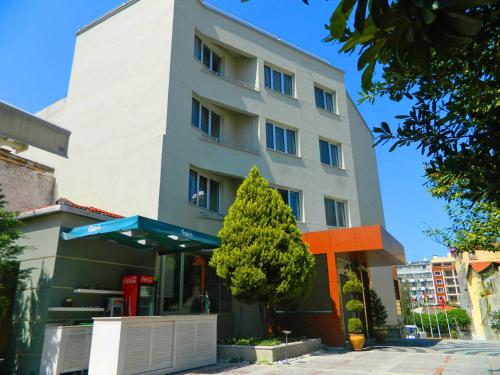 a tall white building with a tree in front of it at Hotel Baylan İzmir in Izmir