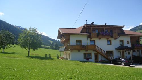 a house on a hill with a car parked in front at Ferienwohnungen Marchanger in Niederau