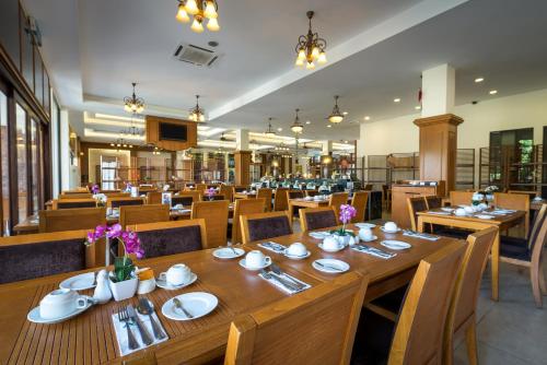 un restaurante con mesa de madera y sillas en Tok Aman Bali Beach Resort @ Beachfront, en Kampong Ayer Tawar