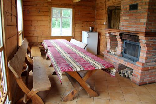 ein Esszimmer mit einem Tisch und einem Kamin in der Unterkunft Zemaite truoba in Milašaičiai