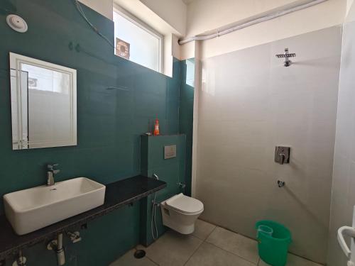 a green bathroom with a sink and a toilet at Hotel Nandaashish in Haldwāni