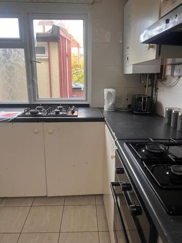 a kitchen with a stove top oven next to a window at Lewisham Rooms in London