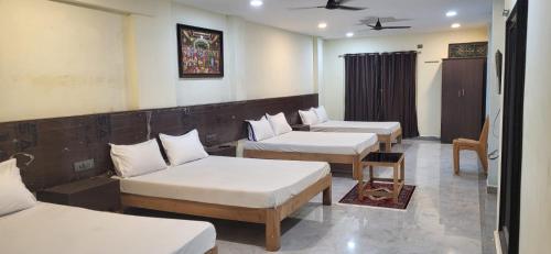 a room with three beds and a couch at SGS Residency in Tirupati