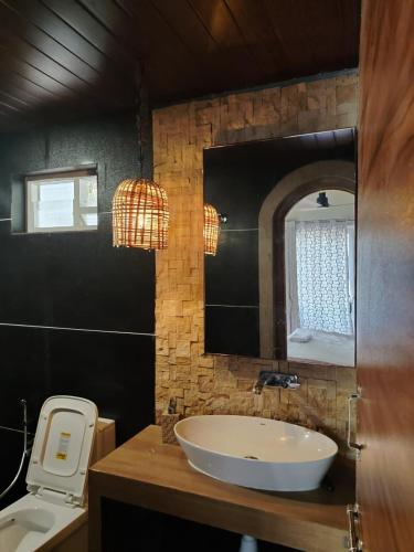 a bathroom with a white sink and a mirror at Arundekar's Cottage in Gokarna