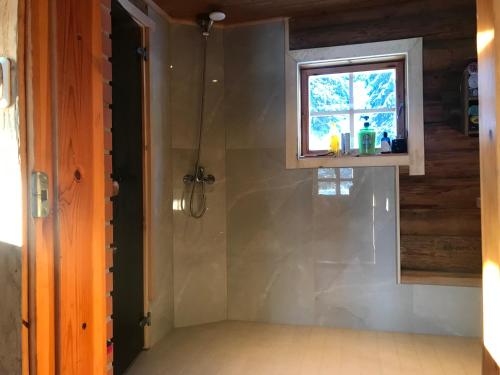 a shower in a bathroom with a window at Ala-Kure metsamaja in Varbuse