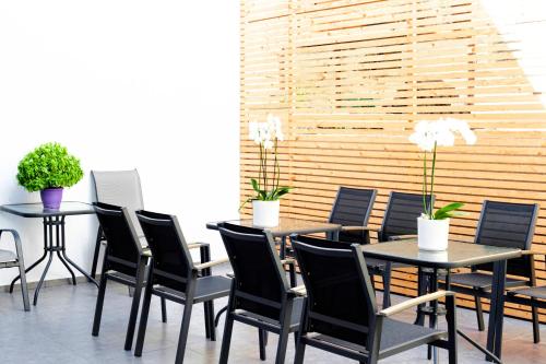 a dining room with black chairs and tables with plants at Atlas Skiathos in Skiathos Town