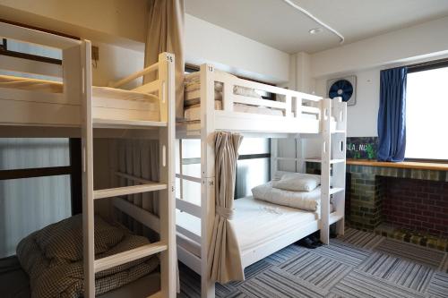 a room with three bunk beds and a window at ゲストハウス ブランク Guest House BLANC in Hiroshima