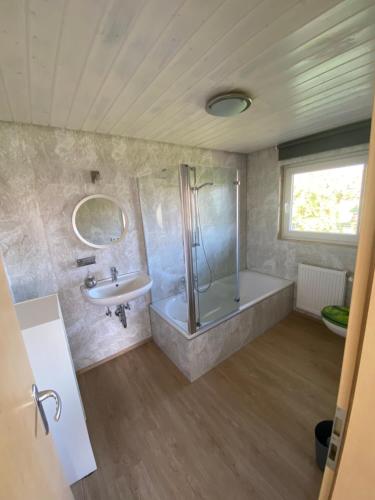 a bathroom with a shower and a tub and a sink at Grünes Allgäu in Opfenbach