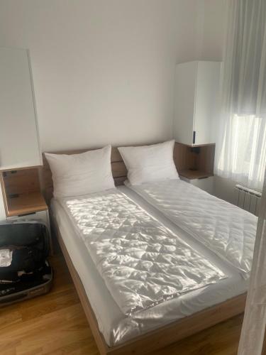 a bed with white sheets and pillows in a room at Privatni apartman A15 Vučko Aparthotel in Jahorina