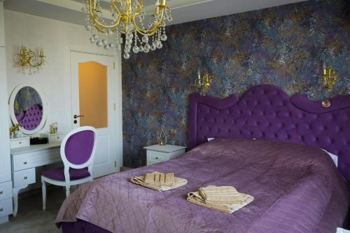 a bedroom with a purple bed and a chandelier at Апартамент за гости Марица in Asenovgrad