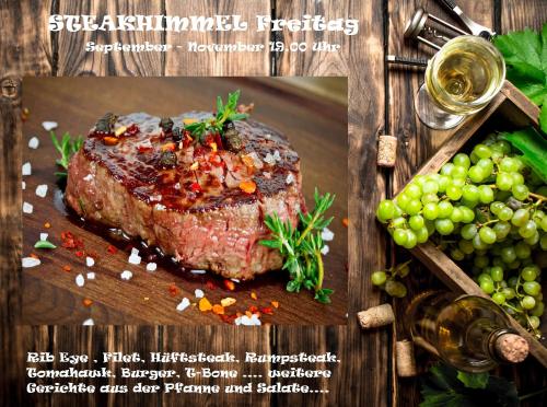 a piece of steak on a cutting board with grapes at Rhönblick Landhotel - Restaurant - Countrypub in Petersberg