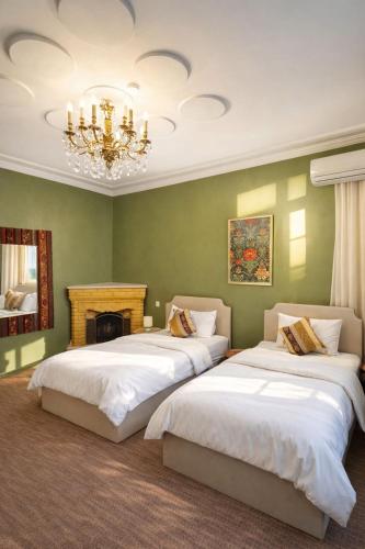 zwei Betten in einem grünen Zimmer mit Kronleuchter in der Unterkunft The Lantern Central Hotel in Baku