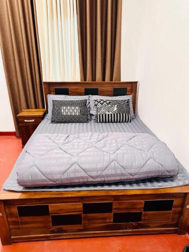 a bed with a wooden frame and pillows on it at D Villa Nuwara Eliya in Sita Eliya