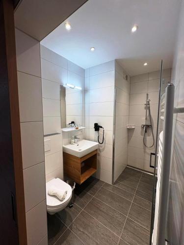 a bathroom with a sink and a toilet and a mirror at Pension Jägerhof in Mallnitz
