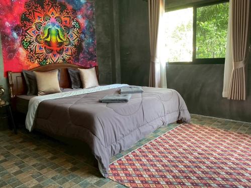 a bedroom with a bed with a painting on the wall at Baan Mada Lanta villa in Ko Lanta