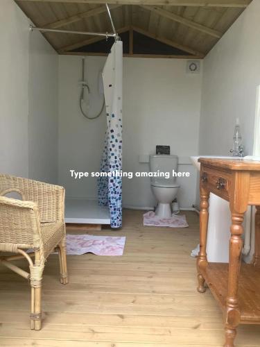 a bathroom with a table and a toilet in a room at Deer Barn Retreats in Hockworthy
