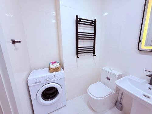 a white bathroom with a washing machine and a toilet at Likas cozy corner in Tbilisi City