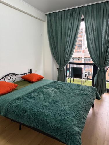 a bedroom with a bed with green sheets and a window at Likas cozy corner in Tbilisi City
