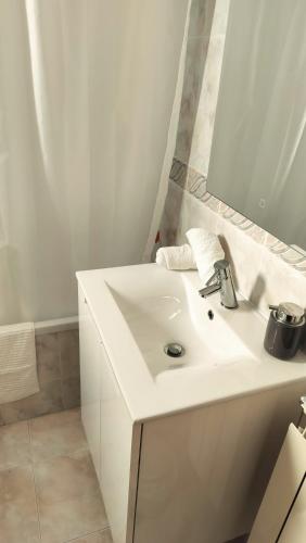 a white bathroom with a sink and a mirror at Xixi Cama Bed & Breakfast in Bombardeira