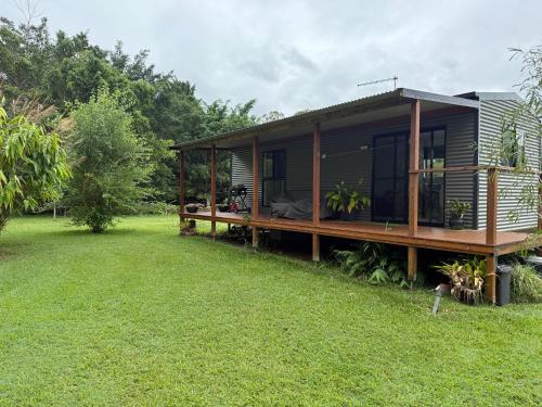 a house with a deck and a grass yard at Private country Cabin 1 Bedroom in Landsborough