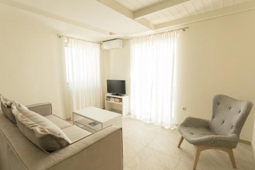 a living room with a couch and a chair and a television at Tseralia Houses in Stoupa