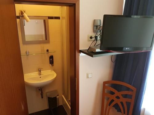 a bathroom with a sink and a tv in a room at Hotel - Restaurant Sophienaue in Eisenach