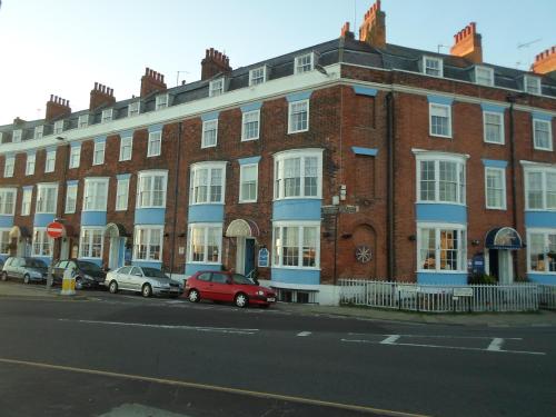 a red brick building with cars parked in front of it at Cavendish House in Weymouth