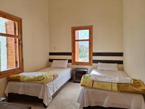 two beds in a room with two windows at Kasbah Anisi in Irhels