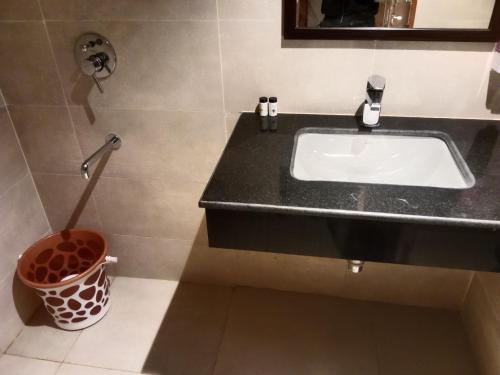 a bathroom with a sink and a trash can at Hotel Maple Tree , Gomtinagar Extension , Lucknow in Lucknow