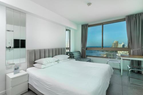 a white bedroom with a large bed and a window at Netanya SeaView ApartHotel in Netanya