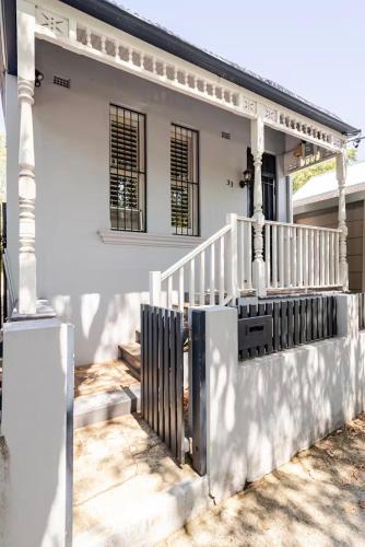 a white house with a porch and a staircase at Cosy Cottage in Annandale in Sydney