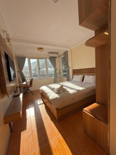 a bedroom with a bed and a desk and windows at FIRONA FLY HOTEL in Sapa
