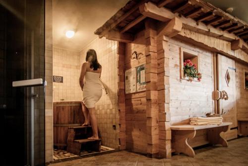 a woman in a white dress standing in a bathroom at Appartement- und Wellnesshotel Winkler in Falzes