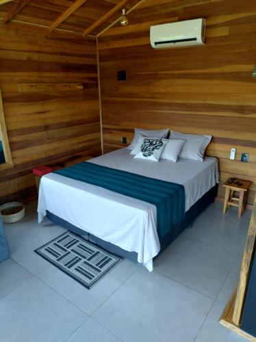 a bedroom with a bed with a wooden wall at Chalé Céu Estrelado in Paraisópolis
