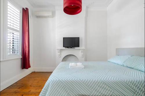 a bedroom with a bed and a tv on the wall at Cosy Cottage in Annandale in Sydney