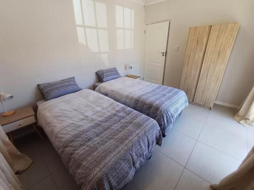 a bedroom with two beds and a door in it at Rees Cottage in Yzerfontein