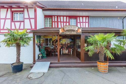 a store with palm trees in front of a building at Motel Steighof in Brütten