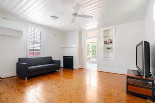 a living room with a couch and a flat screen tv at Cosy Cottage in Annandale in Sydney