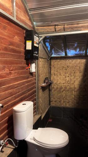 a bathroom with a toilet and a wooden wall at ALAMSUKA Cikole in Tangkubanperahu