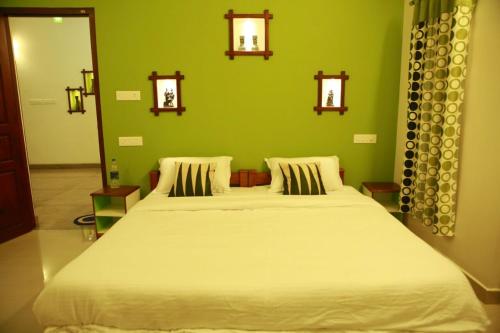 a bedroom with a large white bed with a green wall at Mango Kerala Homes in Kumarakom